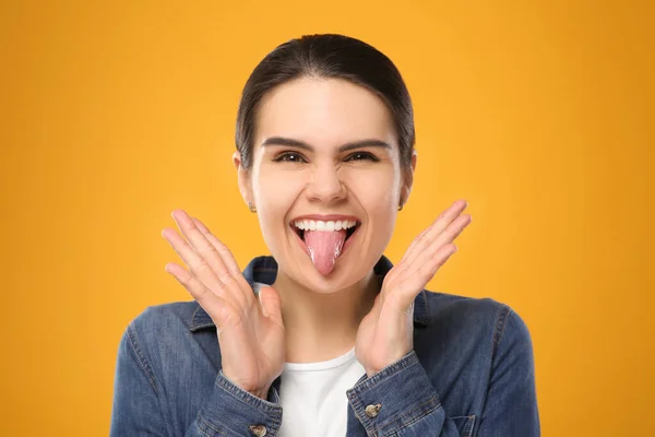 Szczęśliwa Młoda Kobieta Pokazuje Swój Język Żółtym Tle — Zdjęcie stockowe