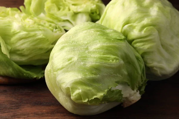 stock image Fresh green whole and cut iceberg lettuce heads on wooden table, closeup