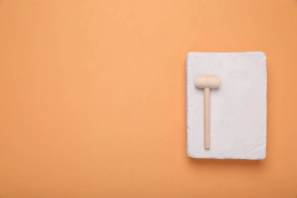 Stock image Educational toy for motor skills development. Excavation kit (plaster and wooden mallet) on orange background, top view with space for text