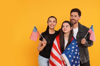 4 Temmuz - ABD 'nin Bağımsızlık Günü. Sarı arka planda Amerikan bayraklı mutlu aile, mesaj için boşluk
