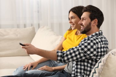 Mutlu çift evde kanepede televizyon izlerken