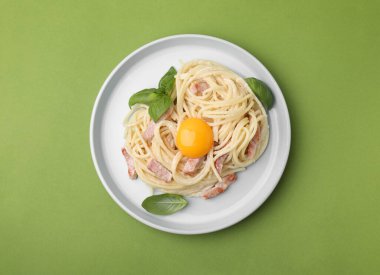 Açık yeşil arka planda yumurta sarısı ile nefis Carbonara makarnası.
