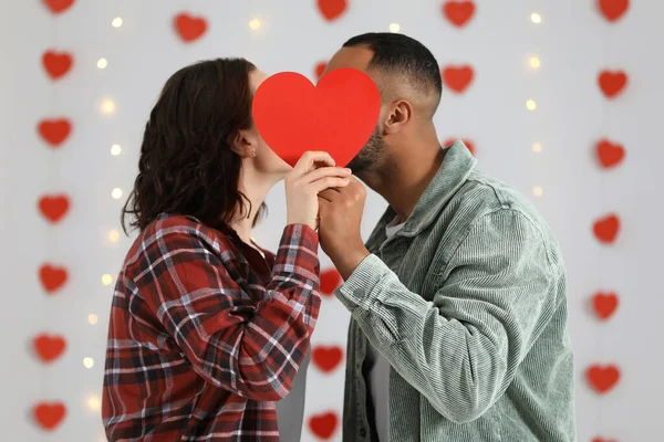 Lovely Couple Kissing Red Paper Heart Indoors Valentine Day Celebration — Stock fotografie