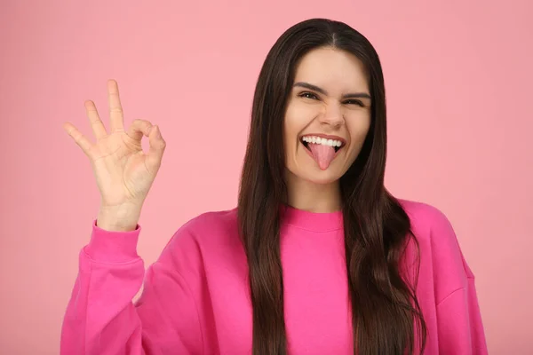 Szczęśliwa Młoda Kobieta Pokazuje Swój Język Gest Różowym Tle — Zdjęcie stockowe