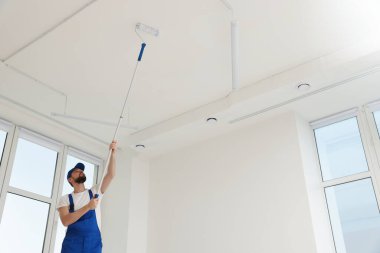 Üniformalı işçiler evin içinde patenlerle tavan boyuyor. Metin için boşluk