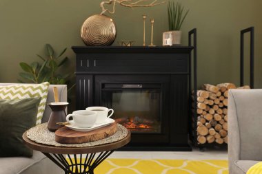 Oturma odasındaki şöminenin yanındaki masada kahve ve kahve fincanları.