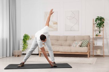 Adam evde spor paspası üzerinde sabah egzersizi yapıyor.