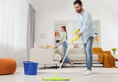 Bahar temizliği. Birlikte oturma odasını toplayan bir çift.