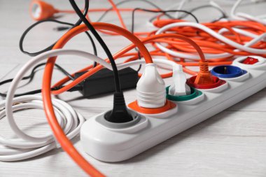 Beyaz kaplamalı zeminde farklı elektrik prizleri olan güç şeridi, yakın plan.