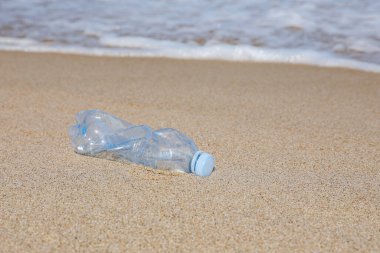 Suyun yakınındaki kumda kullanılmış plastik şişe. Geri dönüşüm sorunu