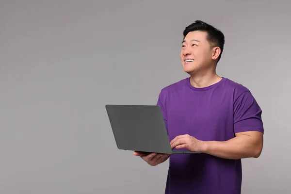 灰色の背景にノートパソコンを持つ幸せな男 テキストのためのスペース — ストック写真
