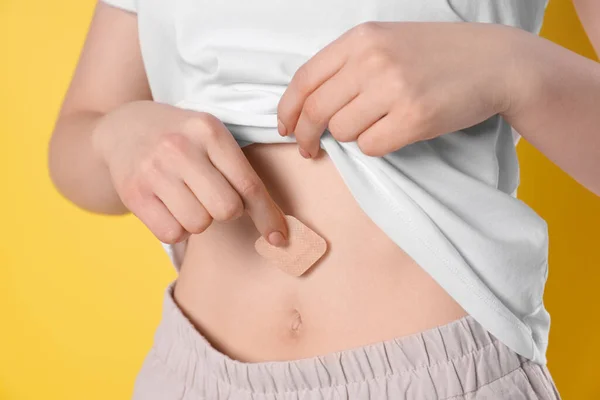 Woman Applying Contraceptive Patch Her Belly Yellow Background Closeup — Foto de Stock
