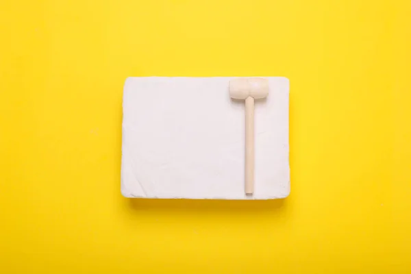 stock image Educational toy for motor skills development. Excavation kit (plaster and wooden mallet) on yellow background, top view