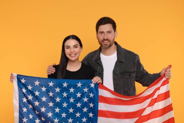 4 Temmuz - ABD 'nin Bağımsızlık Günü. Sarı arka planda Amerikan bayrağı taşıyan mutlu çift