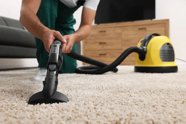 Dry cleaner's employee hoovering carpet with vacuum cleaner indoors, closeup. Space for text
