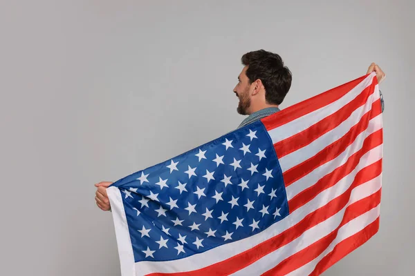 7月4日 アメリカ独立記念日 灰色の背景にアメリカの旗を持つ幸せな男 バックビュー テキストのスペース — ストック写真