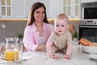 Mutlu genç kadın ve onun tatlı bebeği mutfakta birlikte vakit geçiriyorlar.