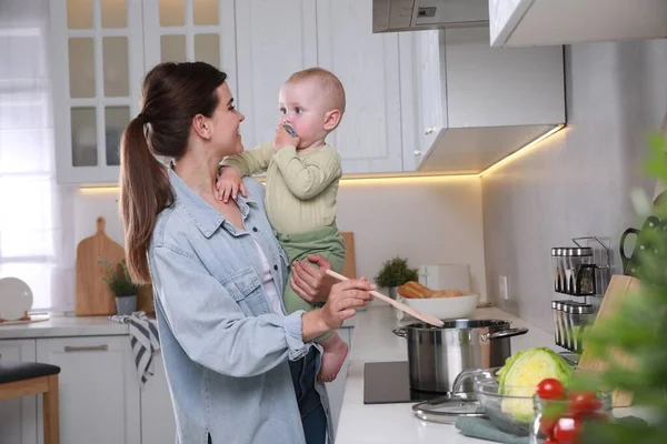 Jovem Feliz Segurando Seu Bebê Bonito Enquanto Cozinha Cozinha — Fotografia de Stock