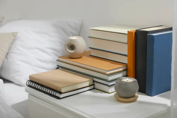 室内白色床头柜上的精装书和香烛 — 图库照片