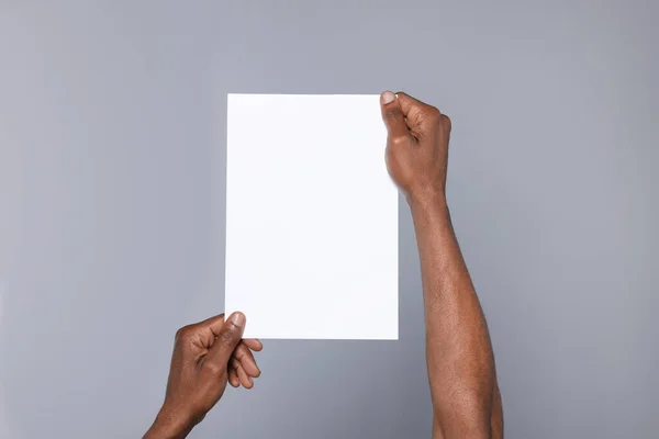 African American Man Holding Sheet Paper Grey Background Closeup Mockup —  Fotos de Stock