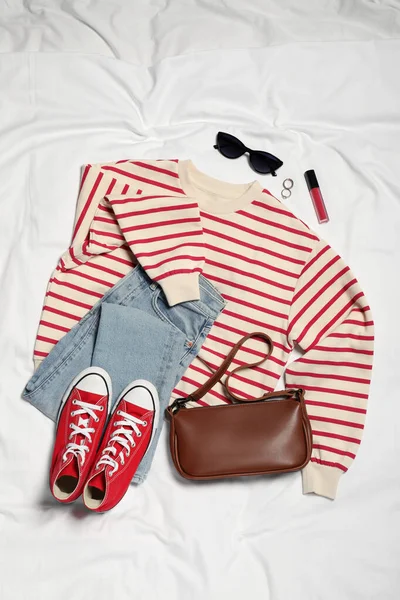 スタイリッシュな赤いスニーカー 白い生地の服やアクセサリーのペア フラットレイ — ストック写真