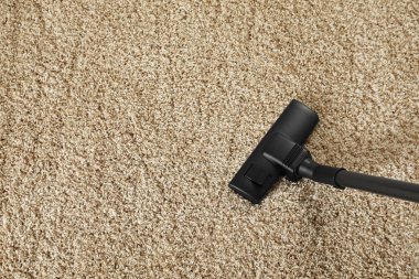 Modern elektrikli süpürgeyle bej halıyı süpürüyor. Metin için boşluk