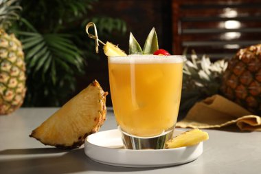 Lezzetli ananas kokteyli ve açık gri masada taze meyve.