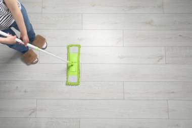 Ahşap zemini paspaslayan kadın, üst manzara. Metin için boşluk