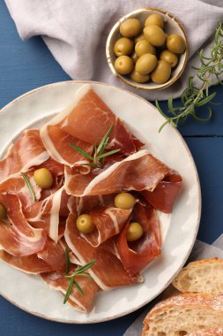 Lezzetli jambon dilimleri, biberiye, ekmek ve zeytin mavi ahşap masa, düz yatıyordu.