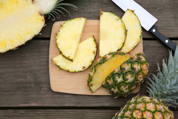 stock image Cut and whole ripe pineapples on wooden table, flat lay