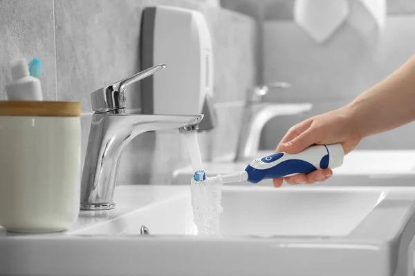 Kobieta Myjąca Elektryczną Szczoteczkę Zębów Pod Bieżącą Wodą Kranu Łazience — Zdjęcie stockowe