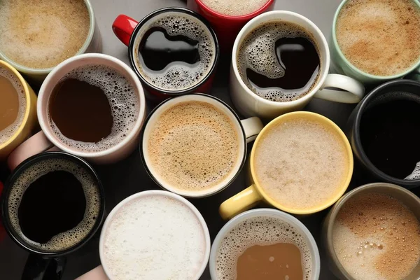 灰色のテーブルの上に芳香のあるコーヒーと多くの異なるカップ フラットレイアウト — ストック写真