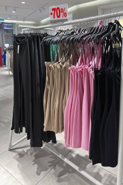 Moda mağazasında şık kadın kıyafetleri koleksiyonu olan indirimli tabela ve askılar.