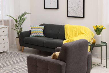 Spring atmosphere. Stylish living room interior with comfortable furniture and bouquet of beautiful yellow tulips