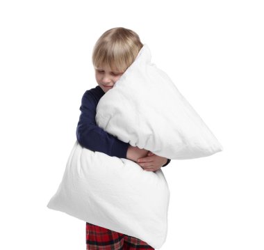 Boy in pajamas hugging pillow on white background