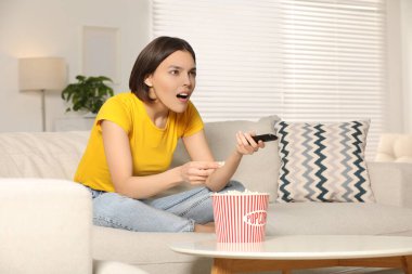 Evdeki kanepede televizyon izlerken patlamış mısır yiyen sürpriz kadın, mesaj atmak için yer.