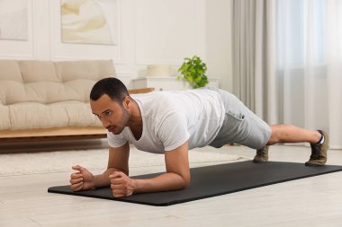 Adam evde spor paspası üzerinde sabah egzersizi yapıyor.