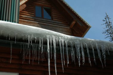 Çatıda buz saçakları olan ev. Kış mevsimi