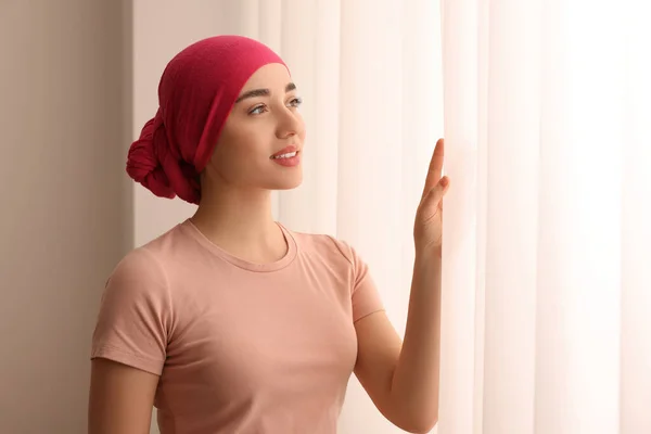 癌症患者 在室内窗户附近戴头巾的年轻女子 — 图库照片