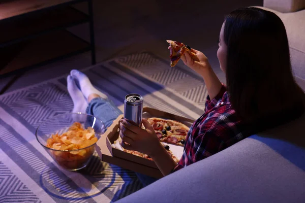 Stock image Young woman eating pizza while watching TV in room at night. Bad habit