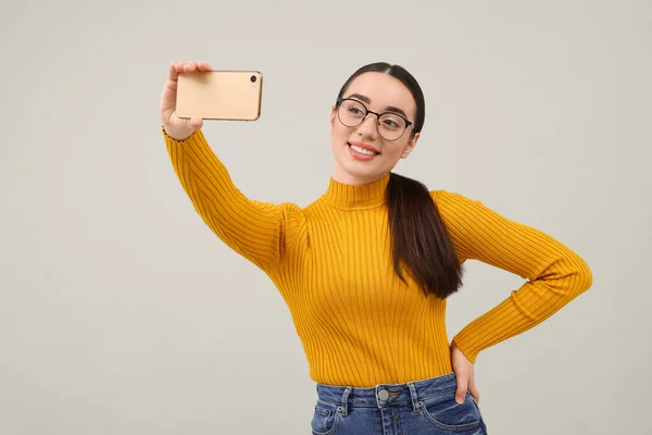Uśmiechnięta Młoda Kobieta Robi Selfie Smartfonem Szarym Tle Miejsce Tekst — Zdjęcie stockowe