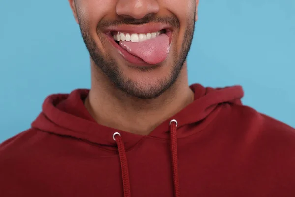 Šťastný Muž Ukazuje Svůj Jazyk Světle Modrém Pozadí Detailní Záběr — Stock fotografie