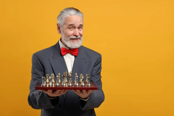 チェス盤とオレンジの背景にゲームの作品を持つ男 テキストのためのスペース — ストック写真
