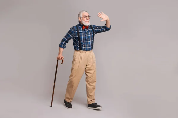 Yaşlı Adam Gri Arka Planda Baston Sallıyor — Stok fotoğraf