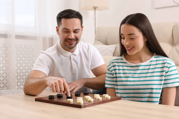 stock image Happy couple playing checkers at table in room