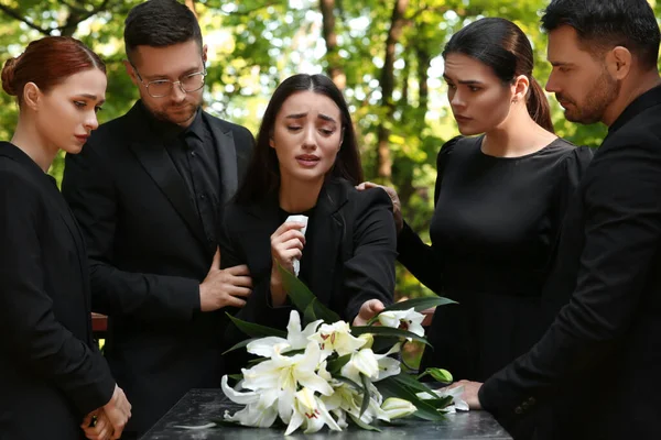 장례식 실외에 묘지에서 백합화와 화강암 근처에서 슬퍼하는 사람들 — 스톡 사진