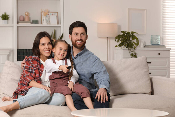 Happy family watching TV on sofa at home, space for text