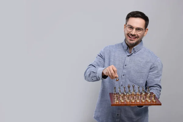 Leende Man Håller Schackbräde Med Spelpjäser Ljusgrå Bakgrund Utrymme För — Stockfoto