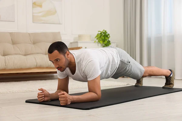 stock image Man doing morning exercise on fitness mat at home