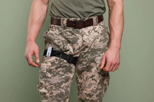 Homem Uniforme Militar Com Torniquete Médico Perna Contra Fundo Oliva — Fotografia de Stock